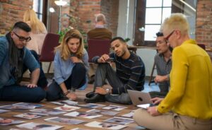 A group of marketing specialists sitting on the floor looking at photos.